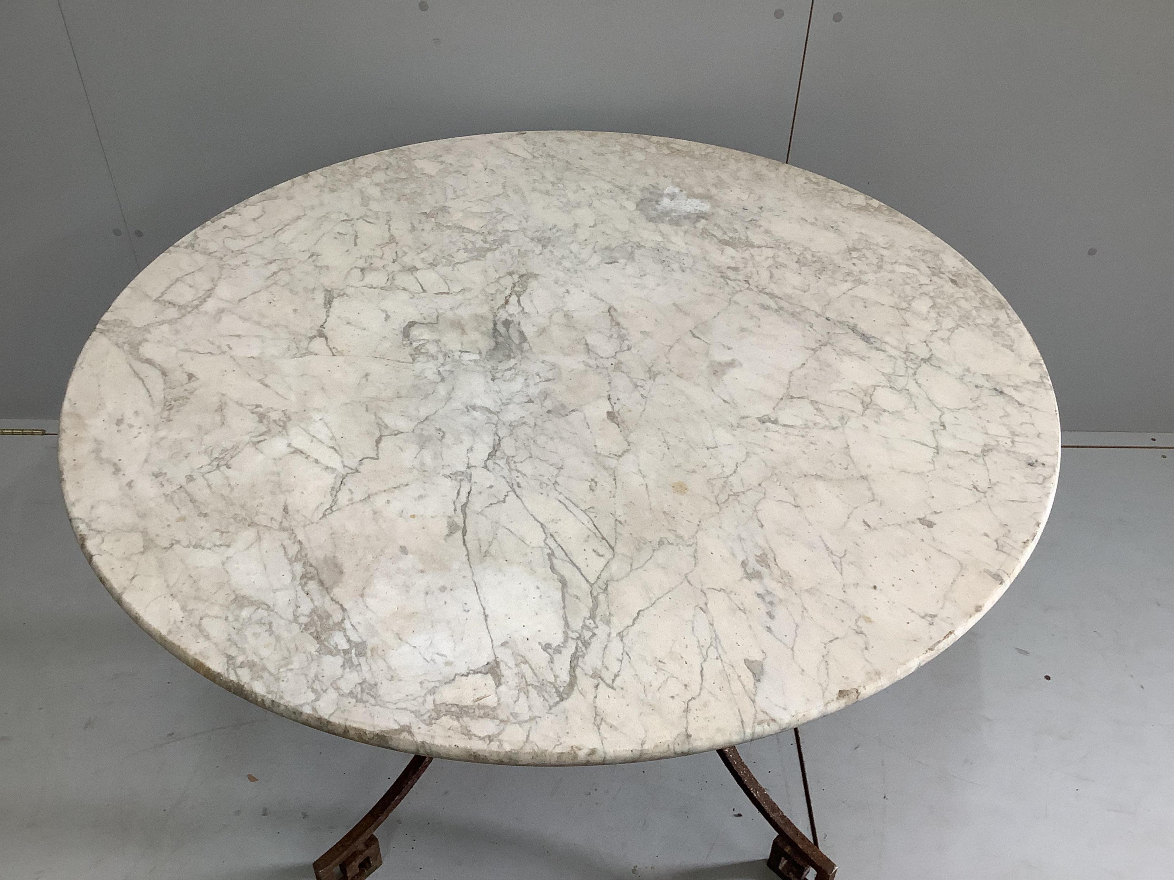 A circular wrought iron white marble topped garden table, diameter 120cm, height 73cm. Condition - good